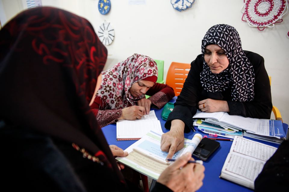 Falha Abrabo assists her students in one of the daily literacy lessons that she gives at the UN Women Oasis in Za’atari refugee camp. Photo: UN Women/Lauren Rooney