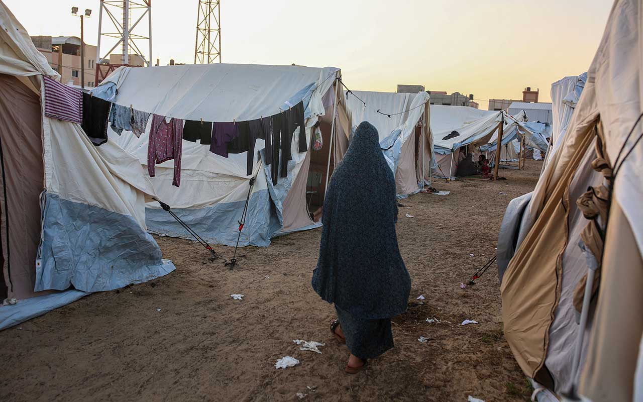 A Palestinian woman walks next to tents in a camp in Khan Yunis, south of the Gaza Strip.