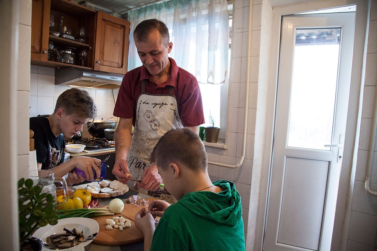 A father cooks with his children in Chishinau, Moldova. 