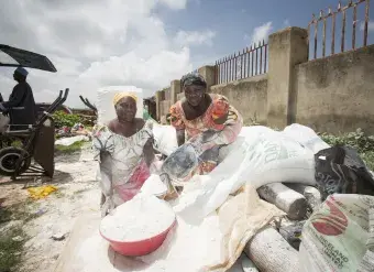 Women sell cassava flour at a market in Abuja, Nigeria. In Nigeria, cassava flour is commonly added to wheat flour produced from imported wheat to lower the cost of making bread, biscuits, cakes and other baked goods. Photo: IFPRI/Milo Mitchell