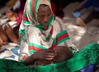 A Somalian woman, displaced by drought and the threat of famine, holds her child. In Somalia and other crisis-affected areas, grain shortages driven by the war in Ukraine are compounding food insecurity. Photo: WFP/Samantha Reinders