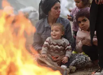 Survivors of the 7.7 magnitude earthquake keep warm by a fire in a temporary shelter in Kahramanmaraş, Turkey. The affected region of south-east Turkey and Syria was already severely disrupted by the nearly 12-year conflict in Syria, and ethnic tensions in Turkey. Photo: UNICEF/Ölçer