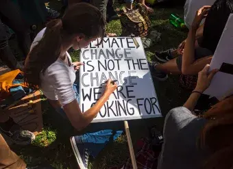 During a demonstration in downtown New York as part of the youth-lead global #ClimateStrike in 2019, a participant creates a sign that reads "Climate Change is not the Change We Are Looking For."  