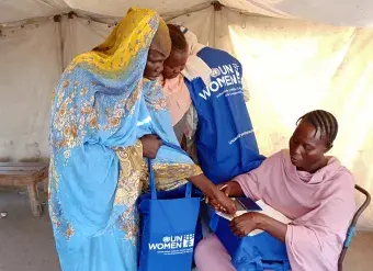 Internally displaced women are seen receiving hygiene kits from a volunteer at a shelter in Port Sudan. 