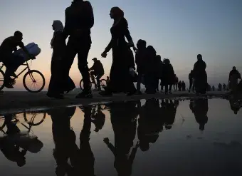 During the sunset, Palestinians walk next to the sea in the city of Rafah, in the southern Gaza Strip, on 8 January 2024.