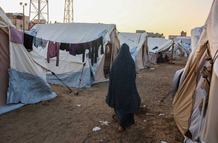 A Palestinian woman walks next to tents in a camp in Khan Yunis, south of the Gaza Strip.